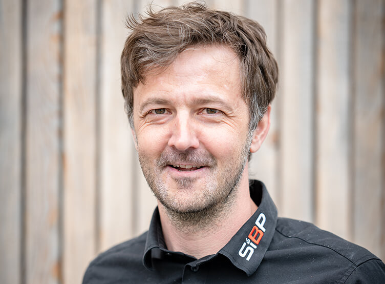 Lächelnder Mann im schwarzen Shirt mit SiBP-Logo.