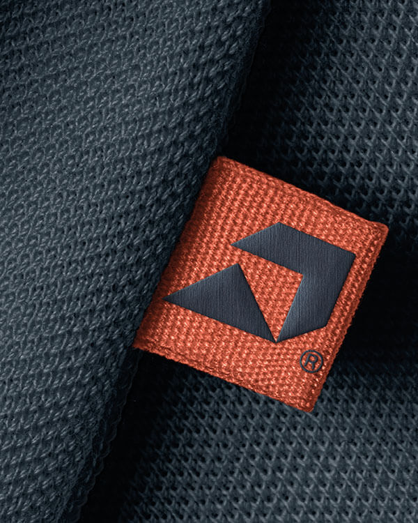 Orange Etikett mit dunklem Logo und ® auf Strickstoff.